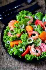 Healthy salad of red and yellow tomatoes, with shrimps, sweet onions, lettuce, balsamic vinegar and olive oil.