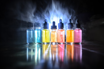 Vape concept. Smoke clouds and vape liquid bottles on dark background. Light effects. Useful as...