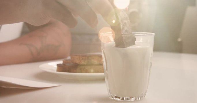 glass with milk and man's hand with cookie. Get wet cookie in milk