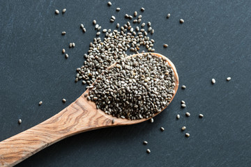 Chia seeds on a wooden spoon on a dark background