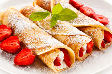 Crepes with strawberries and cream on white background