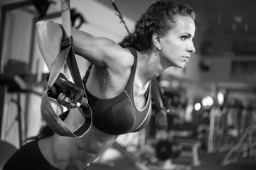 Girl sportswoman doing an exercise on thyrex in the gym