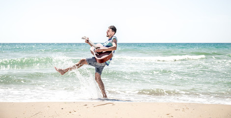 young man with acoustic guitar on the beach