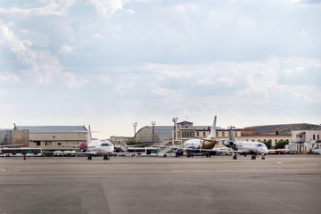 Lots of parked aircrafts in a parking area of a small airport