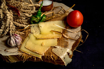 Sliced handmade cheese on a wood board and black background