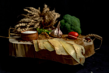 Sliced handmade cheese on a wood board and black background