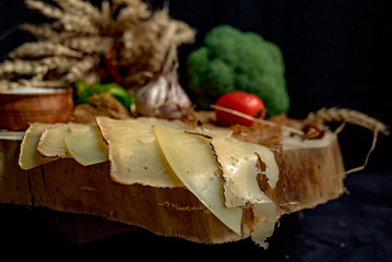 Sliced handmade cheese on a wood board and black background