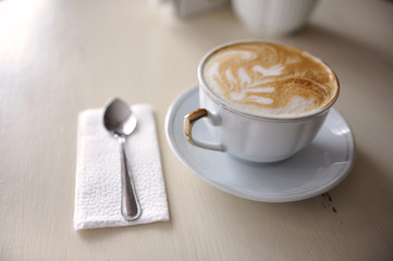 A cup of coffee and a spoon on a vintage table