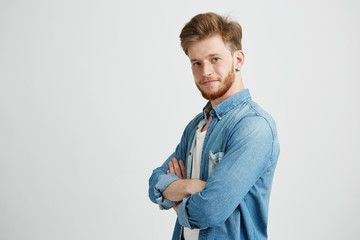 Portrait of confident young handsome man smiling looking at camera with crossed arms over white...