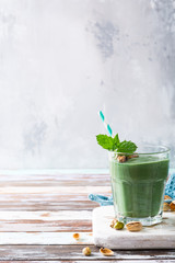 Glass of healthy green pistachio smoothie spirulina on old wooden background. Detox, diet, healthy, vegetarian food concept with copy space.