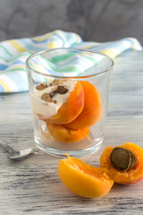 Pieces of peach with cream and nuts with a glass. Peach with a stone in the open form on the table.