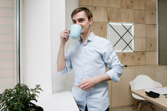 Breake From Work. Smiling Man With Cup Of Coffe Take A Pause From Work In Modern Office