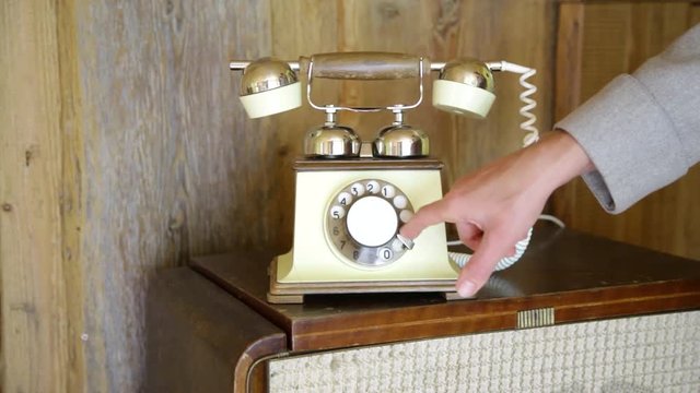 Vintage analog landline telephone dialing by hand finger and picking up the wooden phone with spiral wire