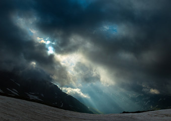 Rising sun is breaking through clouds in the wake of a storm. Caucasus mountains.