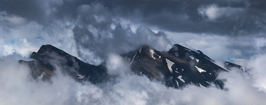 Peaks of ridge Abushura Akhuba jutting out from of cloud. Caucasus mountains.