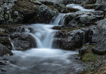 Fototapeta na wymiar Small waterfall on mountain river Zagedanka. Landscape in gray tone. Caucasus mountains.