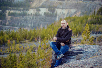 portrait of traveller brunette woman with long straight hair wearing checked shirt and jeans enjoying picturesque sitting on edge enjoying panoramic view of mountains with snow peaks and pine forests