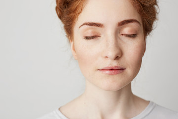 Close up of young beautiful redhead girl with closed eyes over white background. Copy space.