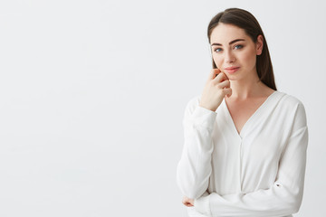 Portrait of young beautiful business lady looking at camera smiling touching face over white background.