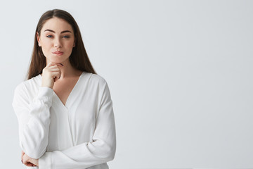 Young beautiful playful businesswoman with cunning tricky glance smiling looking at camera over white background.