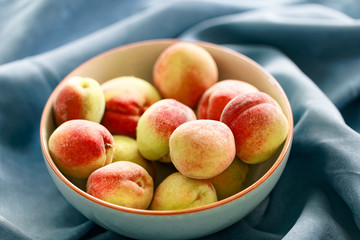 Weinbergspfirsiche in grauer Schale auf blauem Hintergrund