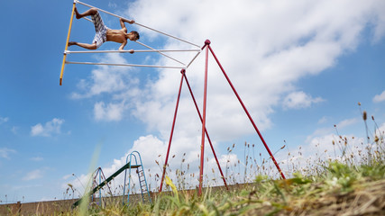Fototapeta na wymiar Boy teenager high riding on a swing, against the sky