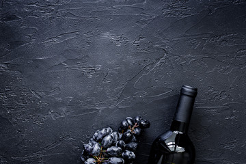 Bottle of wine and grape on black stone table background top view copyspace