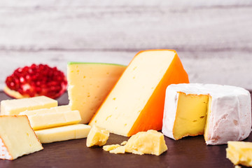 Different types of cheeses and pomegranate  on wooden  background with copy space