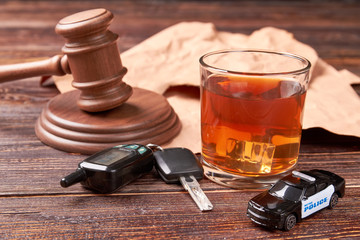 Obraz na płótnie Canvas Booze driving concept. Gavel, driving keys, whiskey, police, wooden background. Hard penalty of drunk driver.