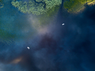 Aerial view of the lake with two boats and reflecting clouds 