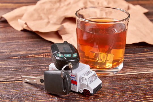 Car key on toy ambulance. Ambulance, car key, whiskey, paper on wooden background. The concept of drink driving.