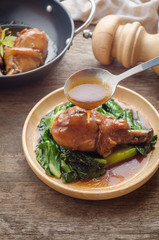 Baked chicken leg with vegetables and sauce on rustic wooden background