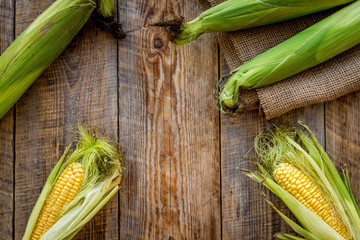 Fresh corn on cobs on rustic wooden table top view copyspace