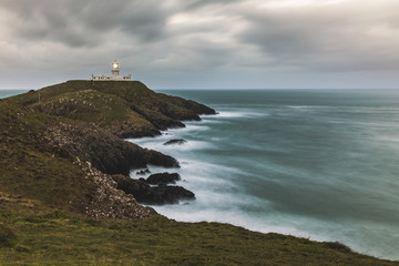 Fototapeta na wymiar Moody seascape with lighthouse on the cliffs