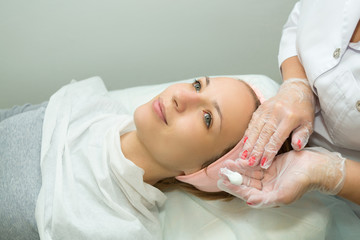 Beautiful young girl on facial cleansing procedure at a cosmetologist