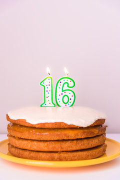 Sixteenth birthday candles on rustic vegan layered cake pastel background