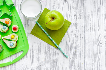 Kids breakfast with funny sandwiches and fruits on light wooden table background top view copyspace