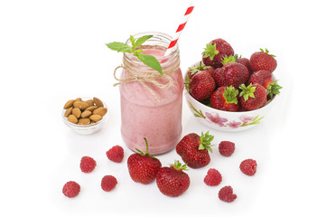 Pink strawberry and raspberry smoothie in a mason jar glass with straw and scattered berries