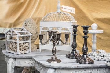 vintage french antique candlesticks and bird cages with price tag at a flea market with a yellow background