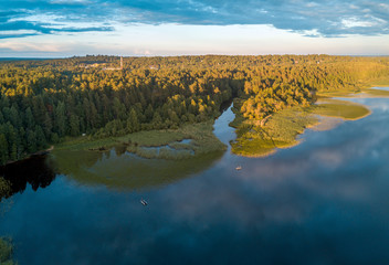 Aerial view of the overgrown shore of the lake with boats at sunset