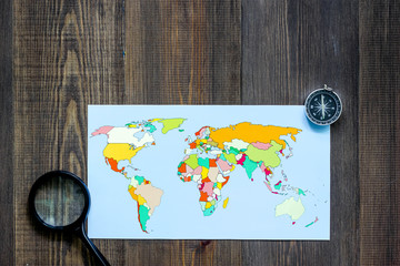 Planning trip. World map and compass on wooden table background top view copyspace