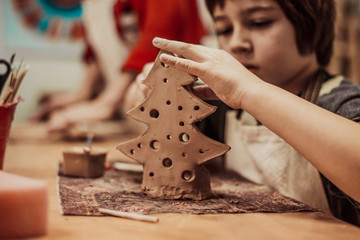The child is engaged in a pottery school, sculpts a clay product © sushytska