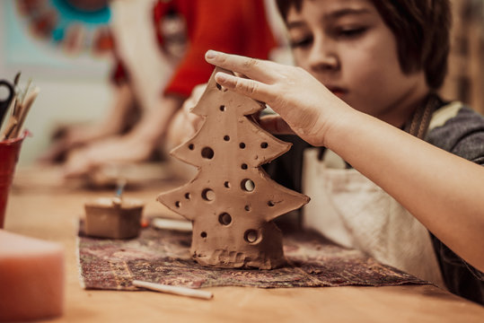 The child is engaged in a pottery school, sculpts a clay product - Powered by Adobe
