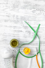 Preparing to feed baby. Puree, spoon, nipple, bottle and bib on light wooden table background top view copyspace