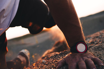 Strong and muscular athlete climbs the hill. Outdoor sports. Smartwatch close-up