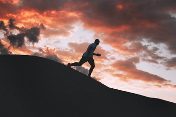 Silhouette of a fast running man on an uneven trail outdoors at sunset