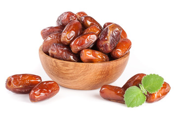 Dates in a wooden bowl with a mint leaf isolated on white background