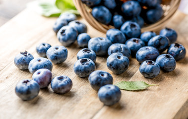 Freshly blueberries on wooden rustic wooden table. Juicy and fresh blueberries with green leaves. Bilberry on wooden background. Blueberry antioxidant. Concept for healthy eating and nutrition.