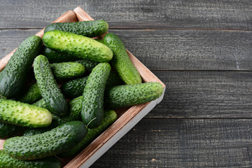 Fresh cucumbers in a wooden box on a black background.