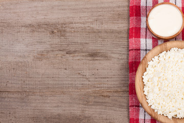 Cottage cheese in a wooden bowl with sour cream on old wooden background with copy space for your text. Top view